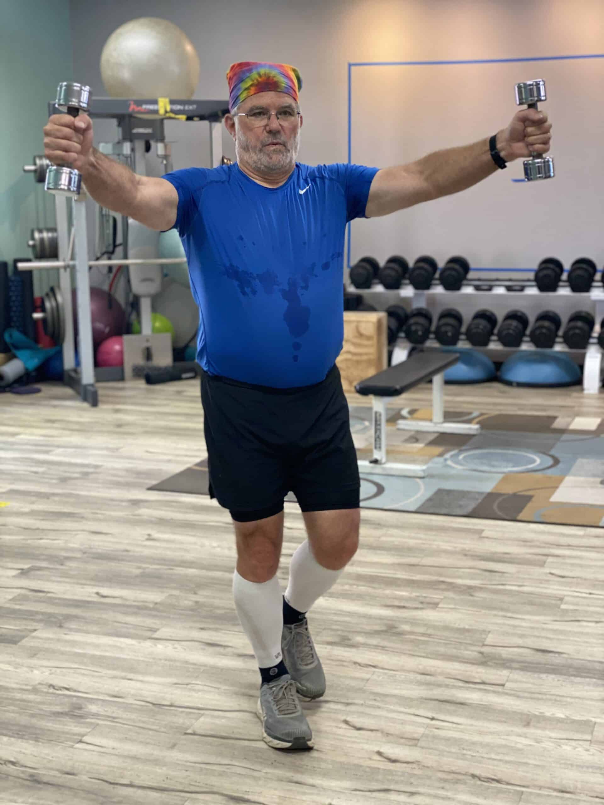 A man lifting dumbbells in a gym.