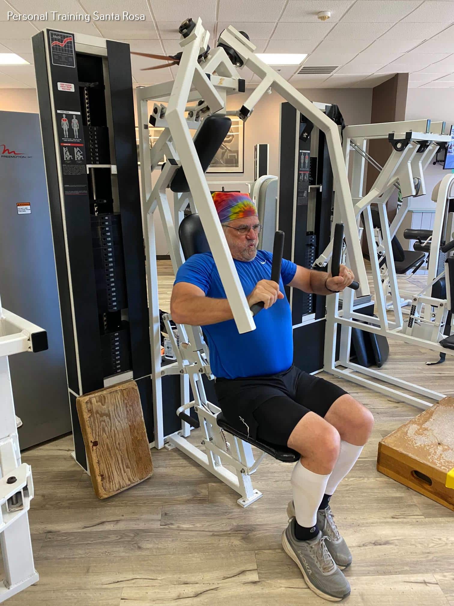 A peaceful man sitting on a machine in a gym.